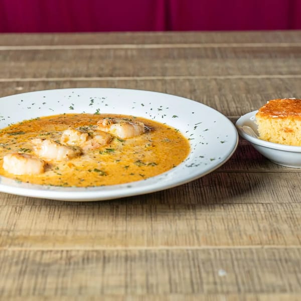 J's Eatery's shrimp and grits with a side of cornbread on a rustic wooden table.