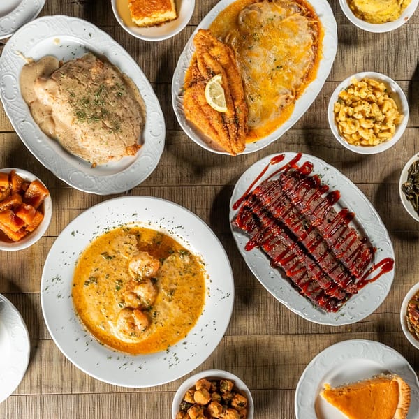 A soul food spread with fried fish, shrimp and grits, meatloaf, mac and cheese, and sweet potato pie.