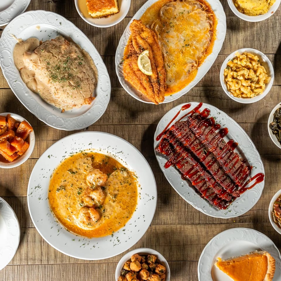 A soul food spread with fried fish, shrimp and grits, meatloaf, mac and cheese, and sweet potato pie.